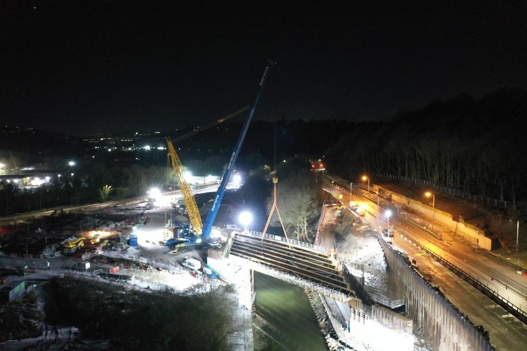 Bridge beams being lowered into place over the canal at night.