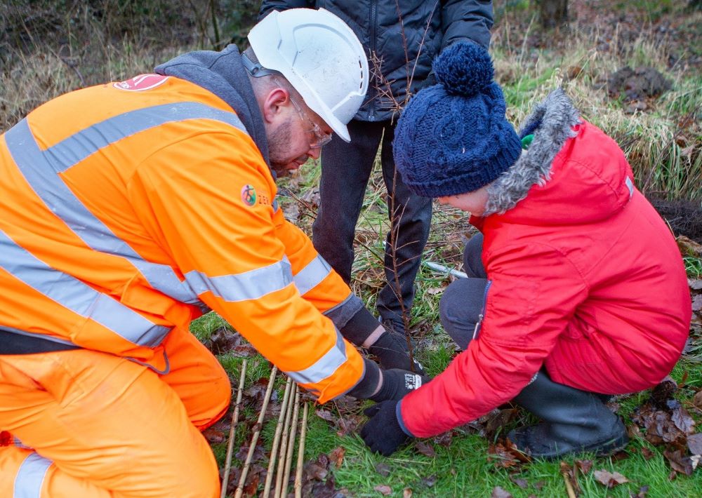 Construction worker helps children to plant trees at Park Wood.
