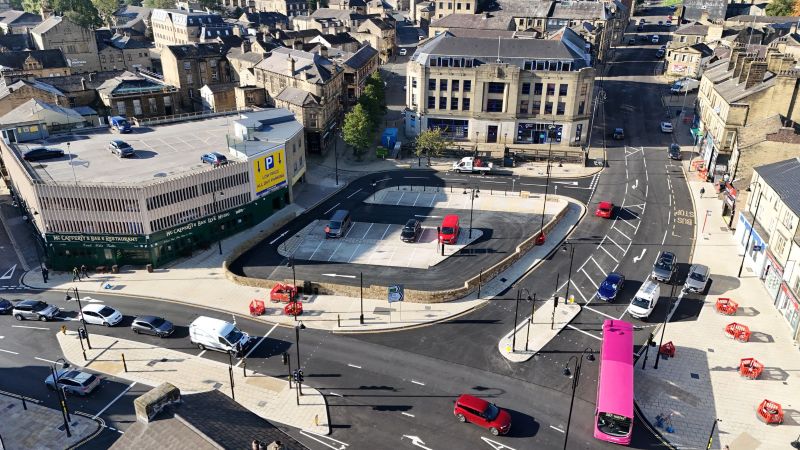 View of Bull Green from above with cars and a bus travelling through the area using the new junction layout and traffic signals. The new Bull Green car park can be seen in the background along with new and improved paving. 