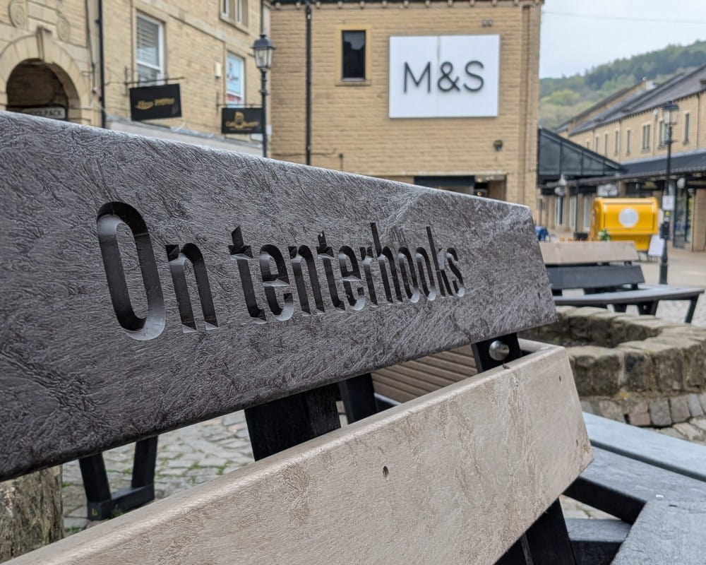 Bench at Woolshops etched with the words "On tenterhooks".
